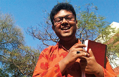 A young man smiling with a book in his hands. 